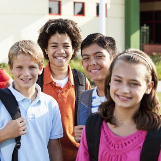 Eine Gruppe Schülerinnen und Schüler stehen auf einer Wiese vor einem Gebäude.