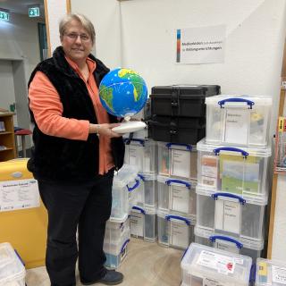 Bibliothekarin Dagmar Schnittker steht vor den Medienkisten in der Ibbenbürener Stadtbibliothek.