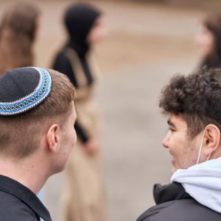 Zwei Jugendliche sind von hinten zu sehen, einer trägt eine Kippa