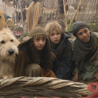 Drei Kinder und ein großer Hund in orientalischer Kleidung schauen erwartungsvoll in die Kamera.