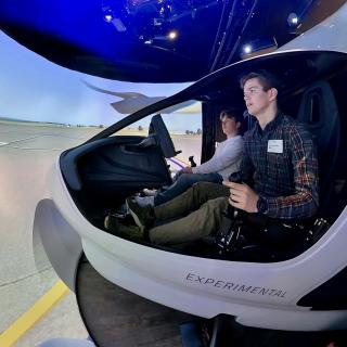 Zwei Schüler sitzen in einem Flugsimulator.