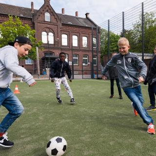 Kinder spielen auf einem Sportplatz Draußen Fußball