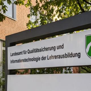 Schild vor einem Gebäude mit der Aufschrift "Landesamt für Qualitätssicherung und Informationstechnologie in der Lehrerausbildung.