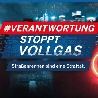 Das Poster zur Kampagne "Verantwortung stoppt Vollgas" zeigt zwei Sportwagen mit roten Bremsleuchten in einer regnerischen Nacht.