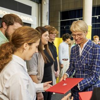 Schulministerin Dorothee Feller überreicht Landessiegerinnen und -siegern des Geschichtswettbewerbs des Bundespräsidenten Mappen mit ihren Auszeichnungen. 