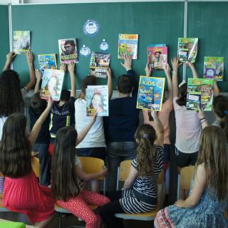 Schülerinnen und Schüler halten verschiedene Zeitschriften aus dem Projekt "Zeitschriften in die Schulen" in die Höhe.