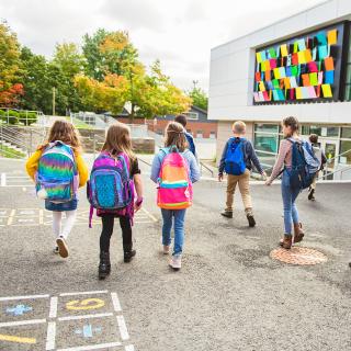 Schülerinnen und Schüler verlassen das Schulgelände.