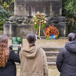 Jugendliche stehen vor einem Gefallenendenkmal.