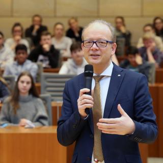 Die Landtagspräsident André Kuper spricht zu Schülerinnen und Schülern.