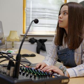 Ein Mädchen sitzt in einem Tonstudio vor einem Bildschirm.