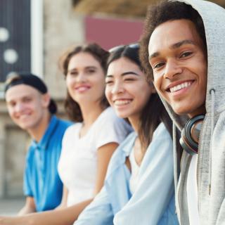 Junge Frauen und Männer lächeln in die Kamera.