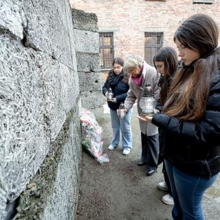 Ministerin Dorothee Feller und Schülerinnen stellen Gedenkkerzen an die Opfer vor der Todeswand neben Blok 11 in Auschwitz auf, wo Erschießungen stattfanden.