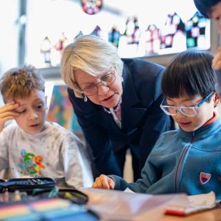 Schulministerin Feller im Austausch mit drei Schülern im Klassenraum.