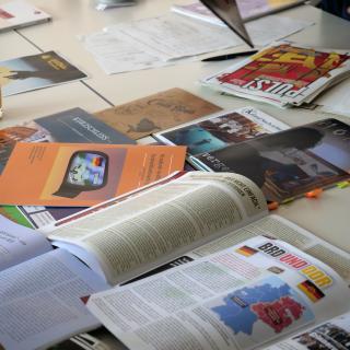 Geöffnete Schülerzeitungen liegen über- und nebeneinander auf einem Tisch.