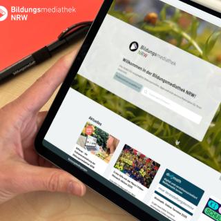 Person hält ein Tablet in der Hand und schaut sich die neue Startseite der Bildungsmediathek NRW an. 