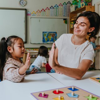 Ein Kind und eine Erwachsene sitzen an einem Tisch mit Spielen.