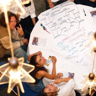 Junge Menschen sitzen gemeinsam um einen Tisch und arbeiten zusammen im Projekt MILeNa.