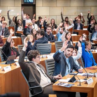 Schülerinnen und Schüler nehmen an einem Aktionstag im Landtag teil und führen eine Abstimmung im Plenarsaal durch.