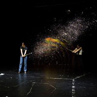 Zwei Schülerinnen schießen auf der Bühne mit riesigen Konfetti-Kanonen.