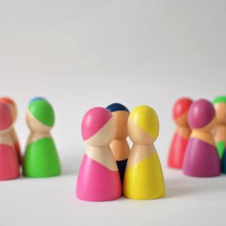 Bunte Holzfiguren stehen in Grüppchen zusammen.