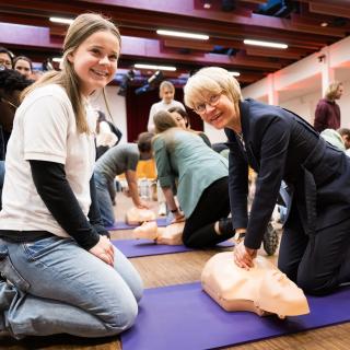 Ministerin Feller demonstriert Reanimation an einer Puppe.