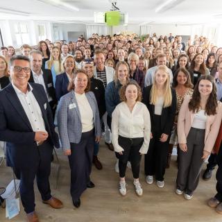 Personen stehen in einem Veranstaltungsraum für ein Gruppenbild zusammen