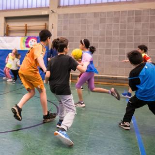 Kinder laufen in einer Turnhalle 