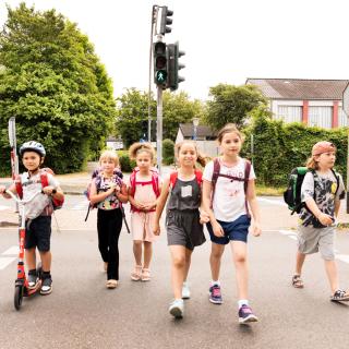 Eine Gruppe Kinder mit Tornistern überquert eine Straße.