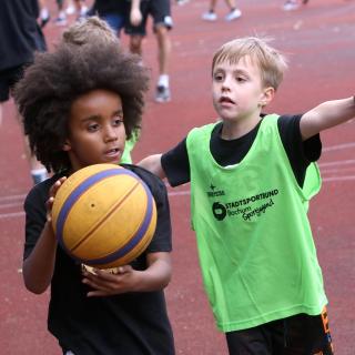 Zwei Jungen spielen Basketball.