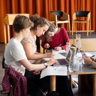 Jugendliche sitzen gemeinsam am Tisch und arbeiten an ihrer Lyrik.