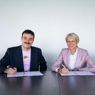 Ministerin Feller und Ludwig Thiede bei der Unterzeichnung des Memorandum of Understanding
