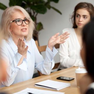 Gesprächsrunde mit mehreren Personen, der Fokus liegt auf einer Frau die engagiert spricht.