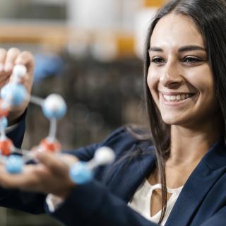 Eine junge Frau betrachtet ein naturwissenschaftliches Modell in ihren Händen..