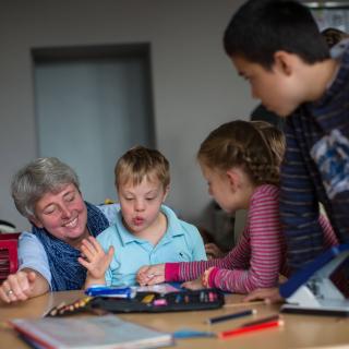 Lehrerin und Kinder mit und ohne Behinderung in Unterrichtssituation