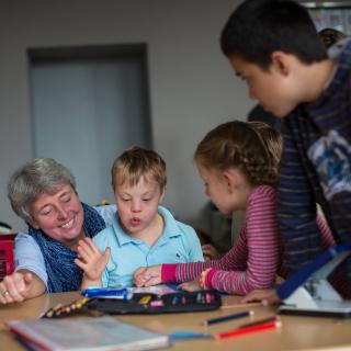 Lehrerin und Kinder mit und ohne Behinderung in Unterrichtssituation