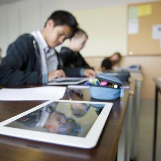 Unterricht in einer Schulklasse. Die Kinder arbeiten mit mobilen Endgeräten 