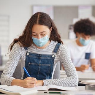 Schülerin mit medizinischem Mund-Nasenschutz im Unterricht