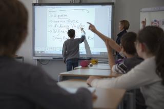 Kind schreibt auf ein Smartboard im Englischunterricht.