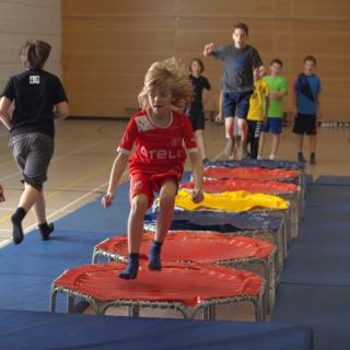 Kinder springen im Sportunterricht auf Minitrampolinen.