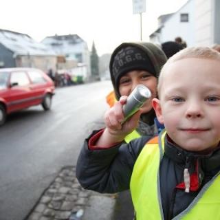 Grundschüler mit Warnweste und Taschenlampe im Straßenverkehr.